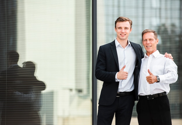 Businessmen thumbs up looking at camera