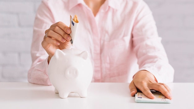 Free Photo businessperson's hand inserting banknote in piggybank