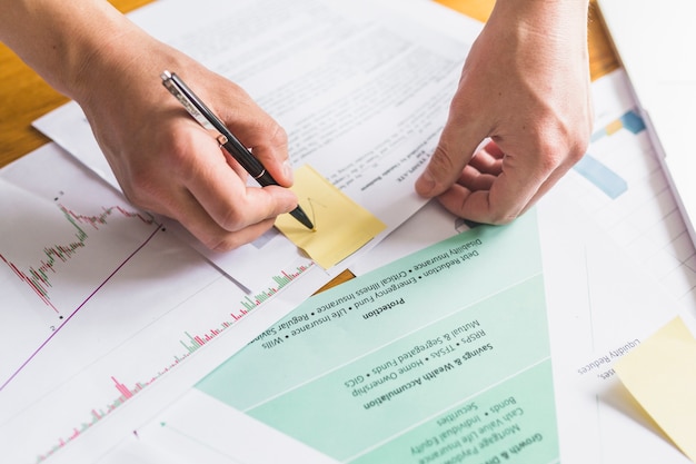 Free photo businessperson's hand marking tick on sticky notes over document