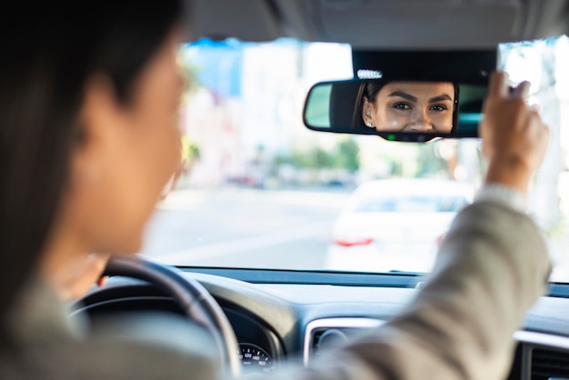 Free photo businesswoman adjusting her rear view car mirror