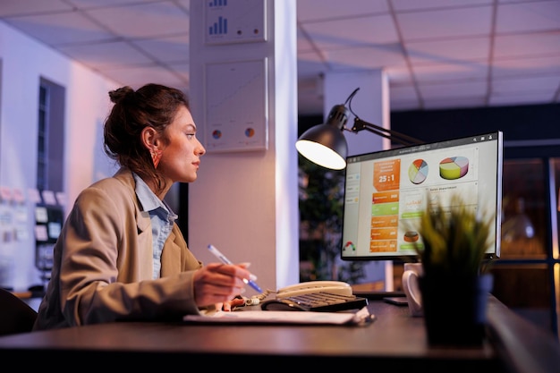 Free photo businesswoman analyzing financial growth report on computer, planning company strategy to increase profit. executive manager working late at night in startup office. corporate concept