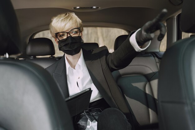 Businesswoman in a black mask sitting inside a car