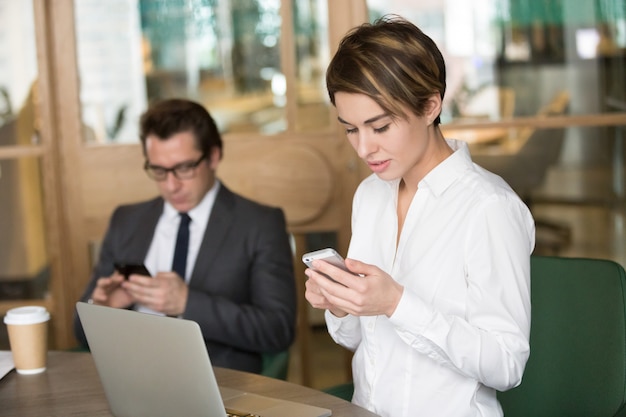 Businesswoman and businessman using mobile phones for work in office