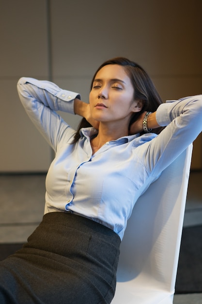 Free photo businesswoman closing eyes and resting on chair