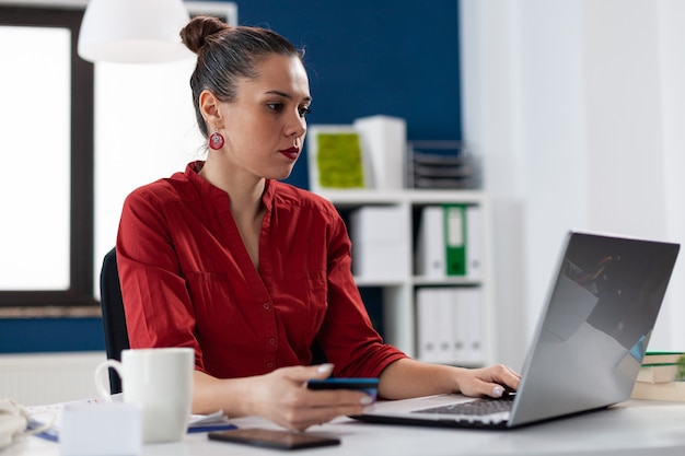 Businesswoman in corporate office workplace holding credit card