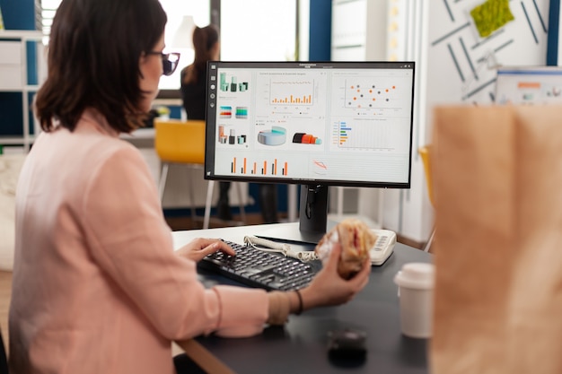 Free Photo businesswoman eating tasty sandwich having meal break working in business company