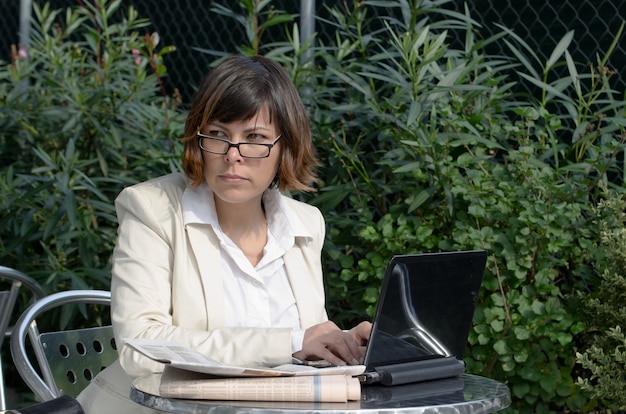 Free Photo businesswoman in glasses sitting at an outdoor table with her laptop