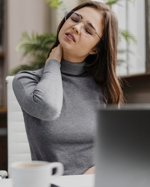 Businesswoman having a neckache while working from home