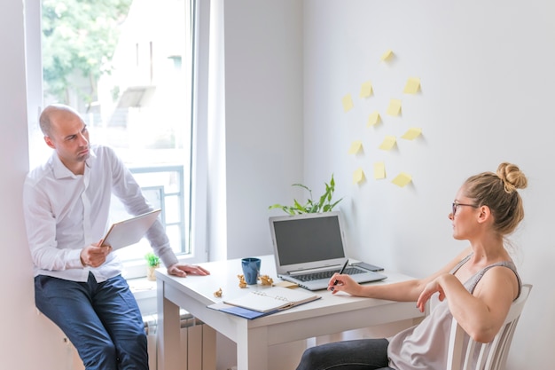 Free Photo businesswoman looking at her partner holding graphic digital tablet in office