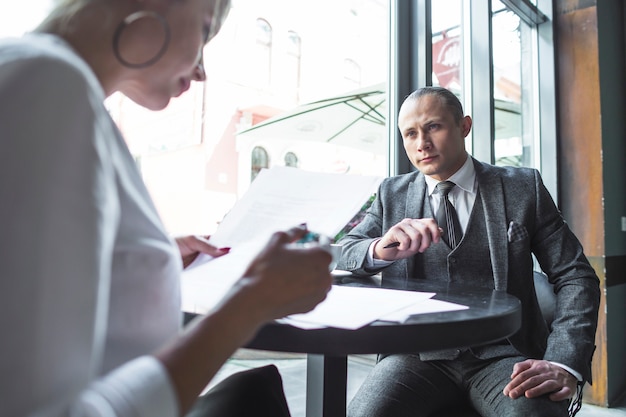 Free Photo businesswoman looking at his colleague examining document in caf�