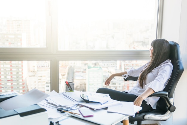 Businesswoman looking out of window sitting in the office