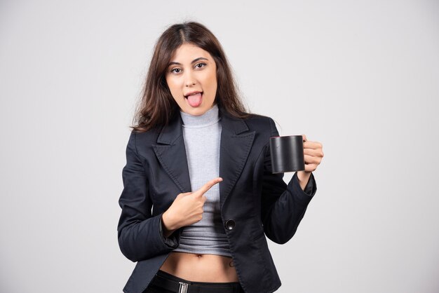 A businesswoman pointing at a cup of coffee or tea . 