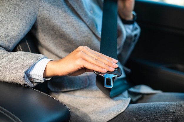 Free photo businesswoman putting on the seat belt in the car