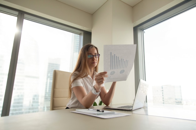 Free photo businesswoman reading document with graphs