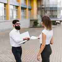 Free photo businesswoman receive document from businessman with city building at background