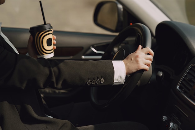 Businesswoman sitting inside a car and drinks a coffee