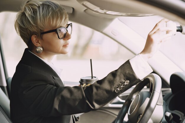 Businesswoman sitting inside a car and drinks a coffee