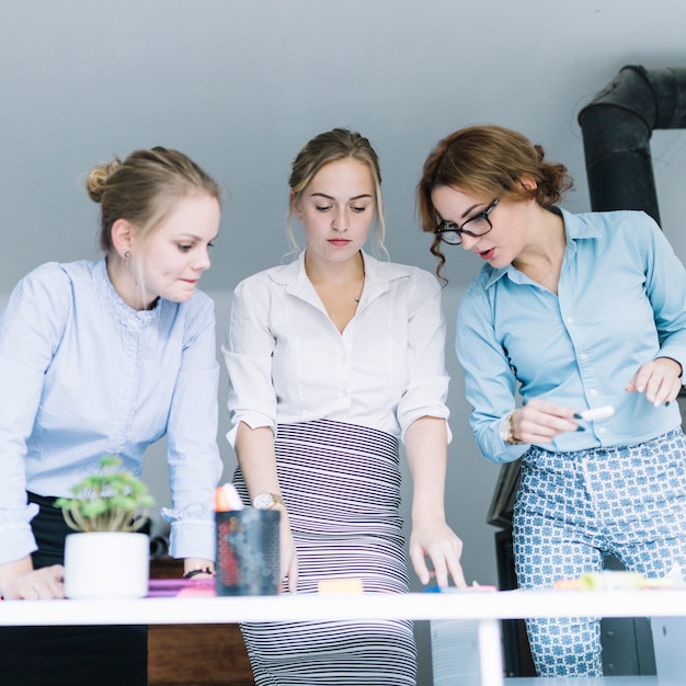 Free photo businesswoman standing behind the office desk planning the business plan