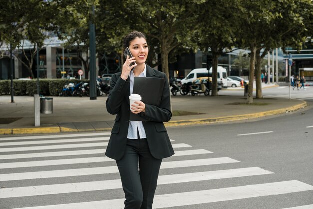 Businesswoman talking on cell phone crossing the road