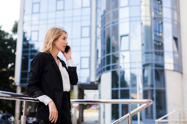 Businesswoman talking on the phone in front of a building