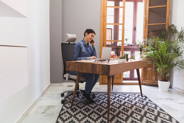 Businesswoman using her laptop and talking on the phone