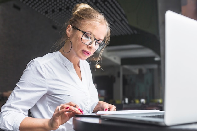 Businesswoman using smartphone while making notes