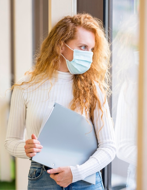 Free photo businesswoman wearing a mask and holding documents