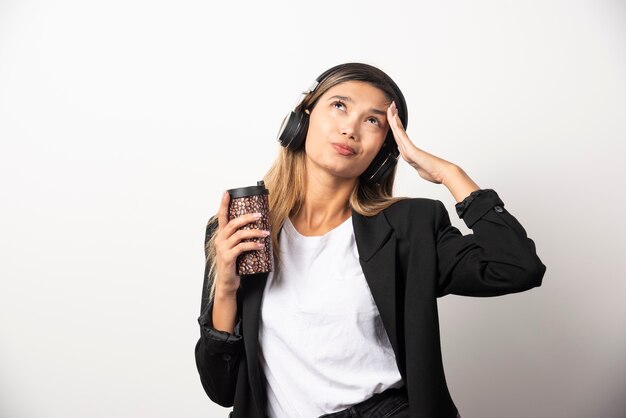 Businesswoman with cup and headphones .