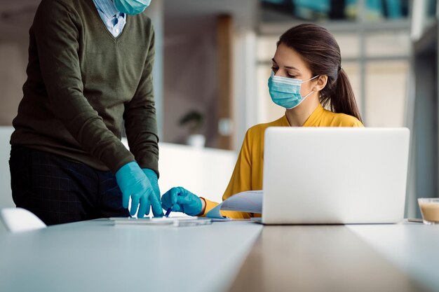 Businesswoman with face masks going through paperwork with her colleague in the office