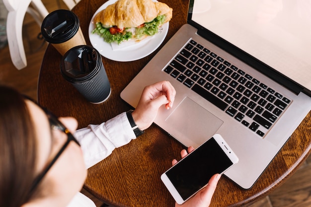 Businesswoman with laptop and smartphone in coffee shop