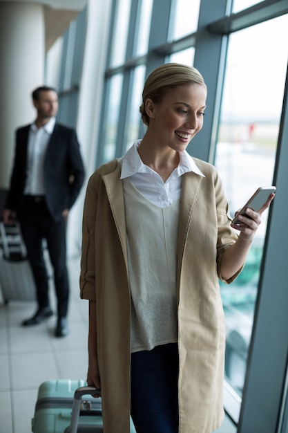 Businesswoman with luggage using mobile phone