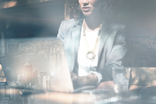 Free Photo businesswoman working on a laptop city background