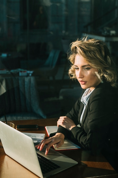 Free Photo businesswoman working on laptop over wooden desk