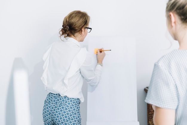 Free Photo businesswoman writing on sticky notes with pencil over white board