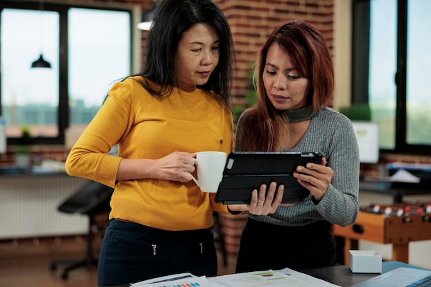 Businesswomen comparing management statistics of this year with last year working at company strategy to increase revenue. Marketing team discussing business partnership ideas in startup office