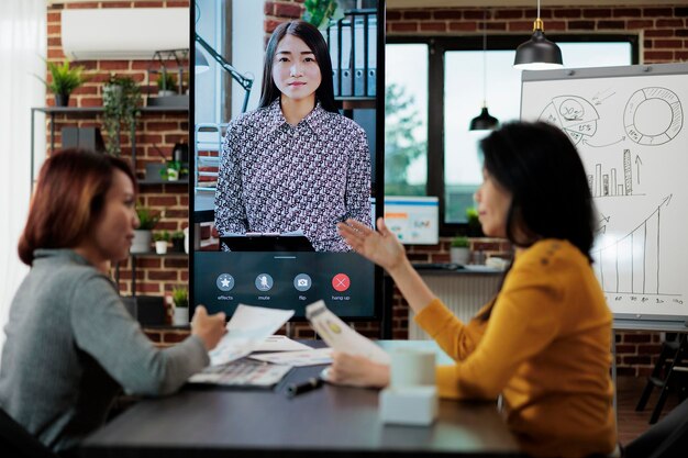 Businesswomen discussing company statistics with remote manager during online videocall meeting conference in startup office. Management team explaining company strategy. Teleconference call