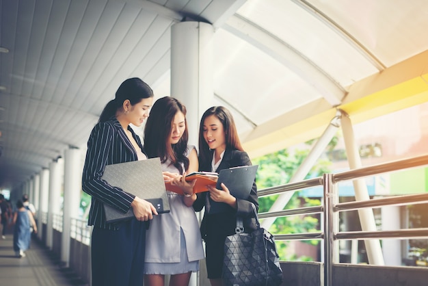 Businesswomen discussing over paperwork together against railing. Business people concept.