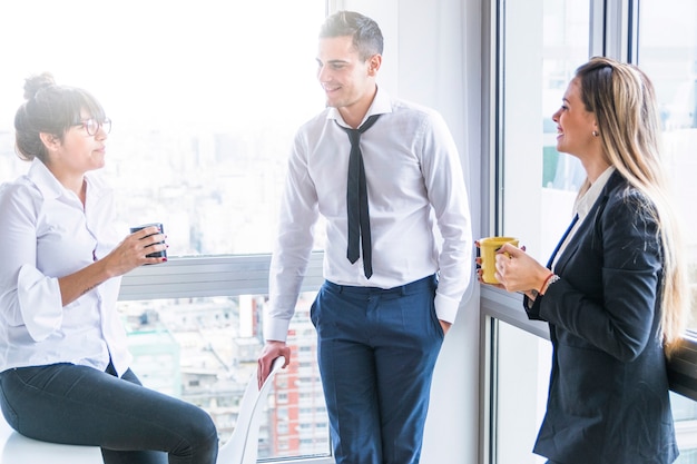 Free photo businesswomen holding coffee cup talking with businessman