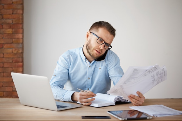 Busy concentrated businessman in glasses and shirt sitting in a comfortable office