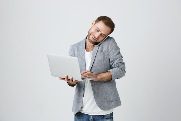 Busy handsome businessman speaking on phone and using laptop