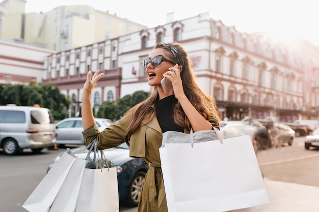 Free photo busy shopaholic woman with bags talking on phone and waiting bus in city