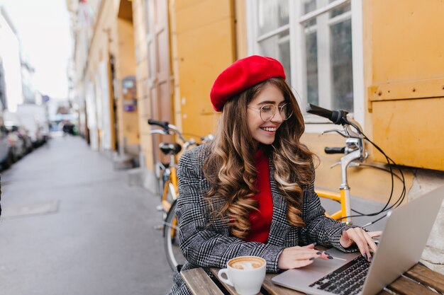 Busy smiling female freelancer spending time in outdoor cafe