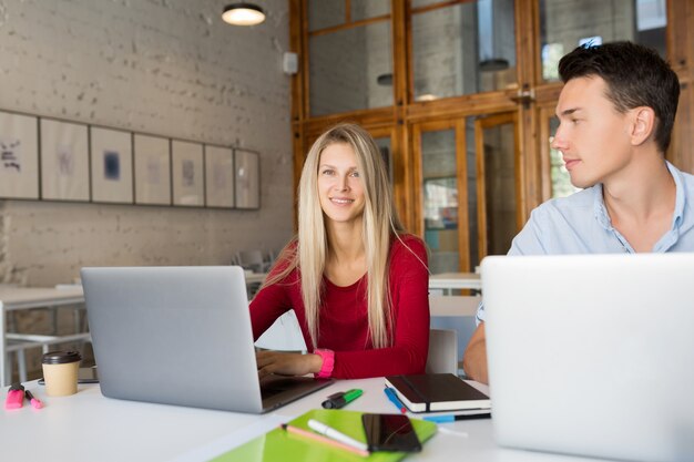 Busy young man and woman working on laptop in open space co-working office room