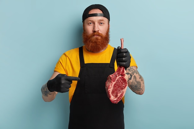 Butcher man with ginger beard holding meat