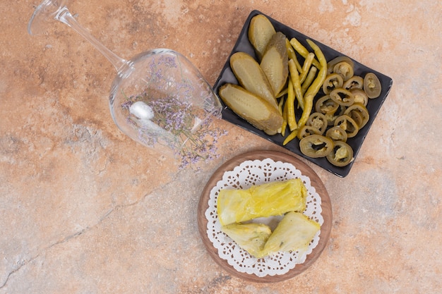 Free Photo cabbage dolma rolls and plate of pickles on orange surface.