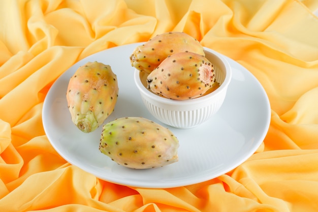 Free photo cactus fruits in a white plate on yellow textile surface