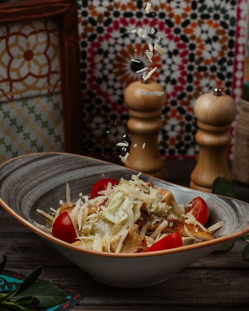 Free photo caesar salad with chopped parmesan and freah cherry tomatoes in a rustic bowl.