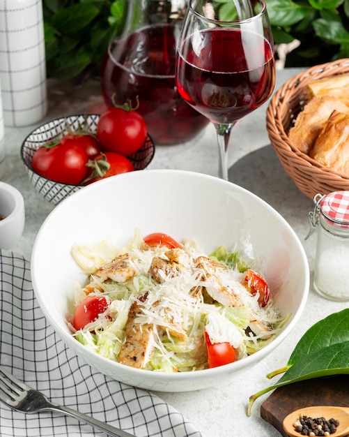 Caesar salad with tomato, lettuce, served with wine