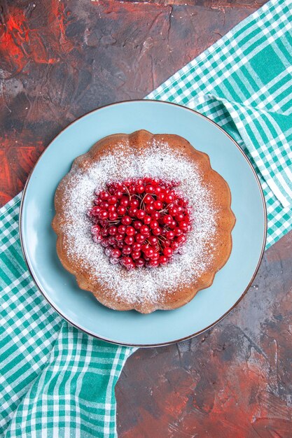 a cake an appetizing cake with red currants on the white-blue tablecloth