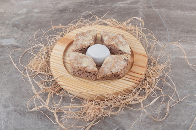 Free photo cake slices around a vanilla powder coated cookie on a wooden plate on marble